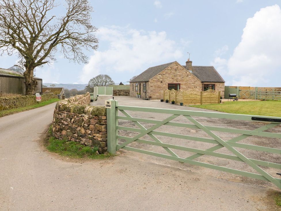 A house with a stone wall and gate at The Lodge in Wirksworth
