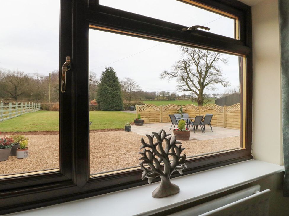 A view of a garden with chairs and a table from a window at The Lodge in Wirksworth