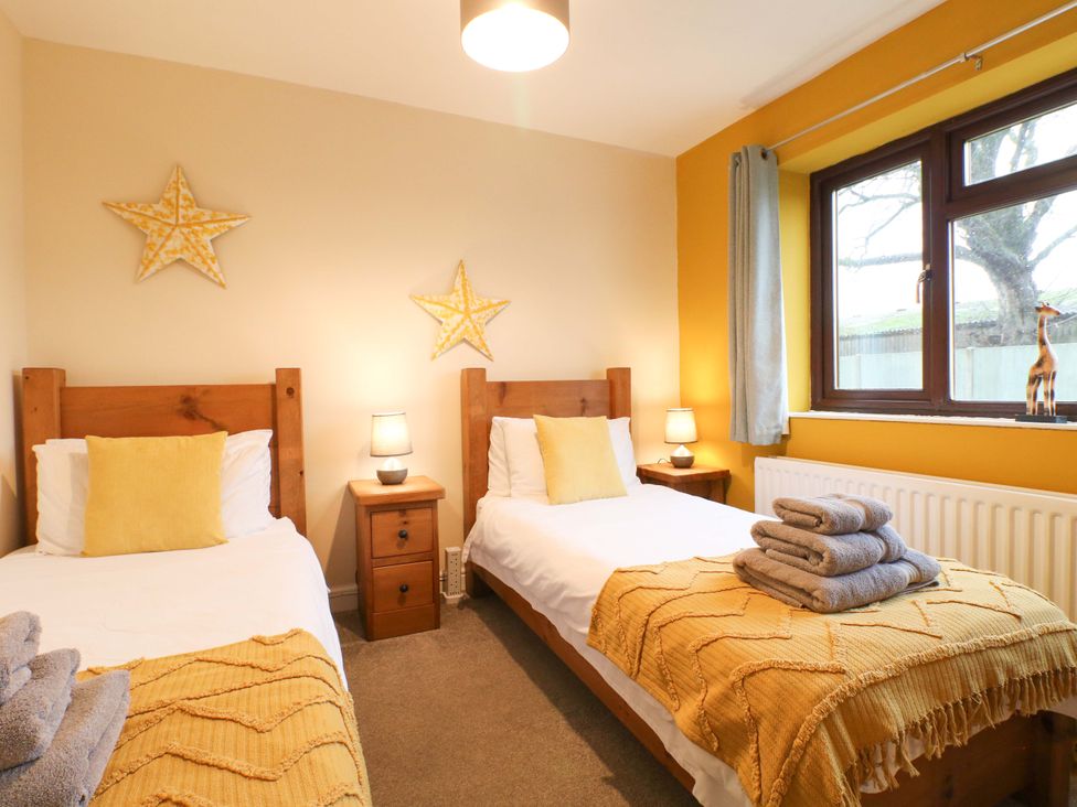 A bedroom with two single beds and a window at The Lodge in Wirksworth
