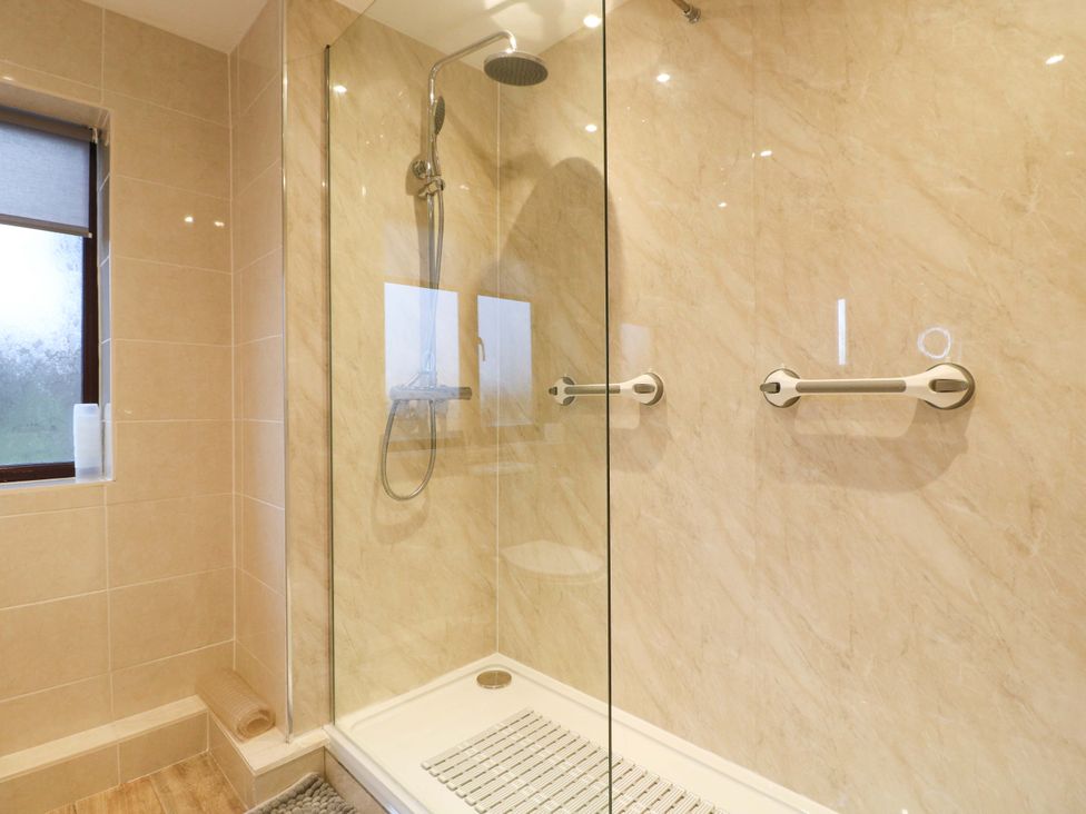 A shower area with a glass screen and fixtures at The Lodge in Wirksworth