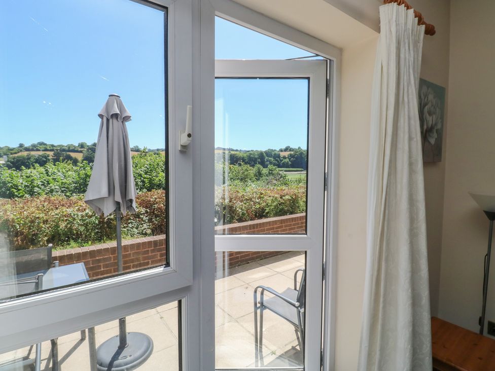 A view through a window with an umbrella and chair at Willow in Newton Abbot