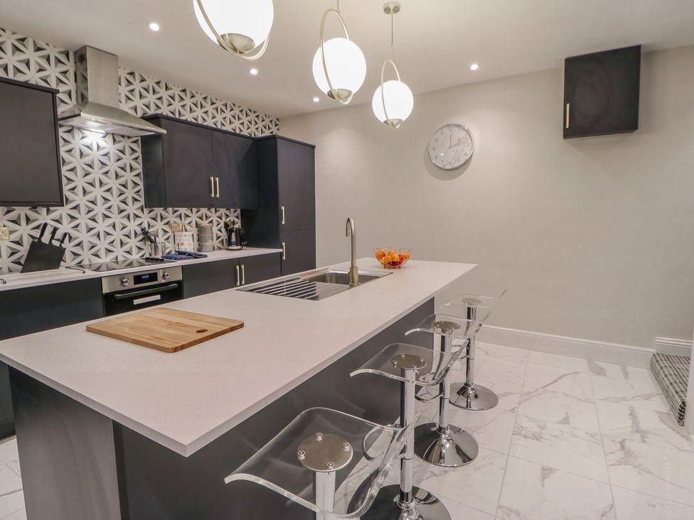 A kitchen with an island and bar stools at 16 Seafield Terrace in South Shields
