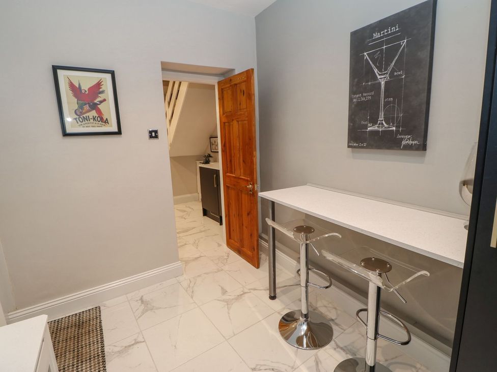 A kitchen with bar stools and a door at 16 Seafield Terrace South Shields