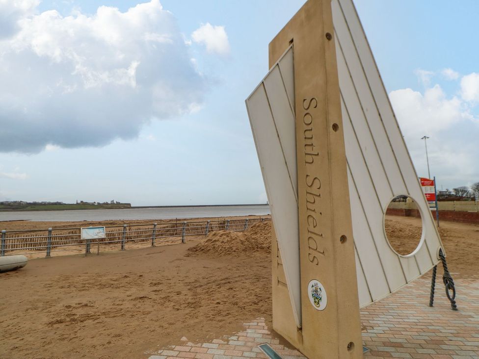 A sign at the beach with text South Shields and a view of the water in South Shields
