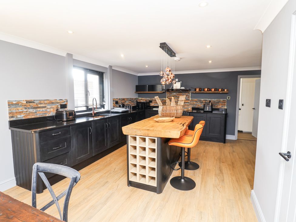 A kitchen with a large island and bar stools at Holly Farm near Brantham