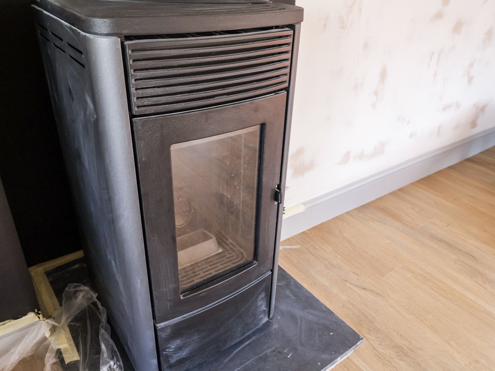 A stove with a glass door in a living room at Holly Farm near Brantham