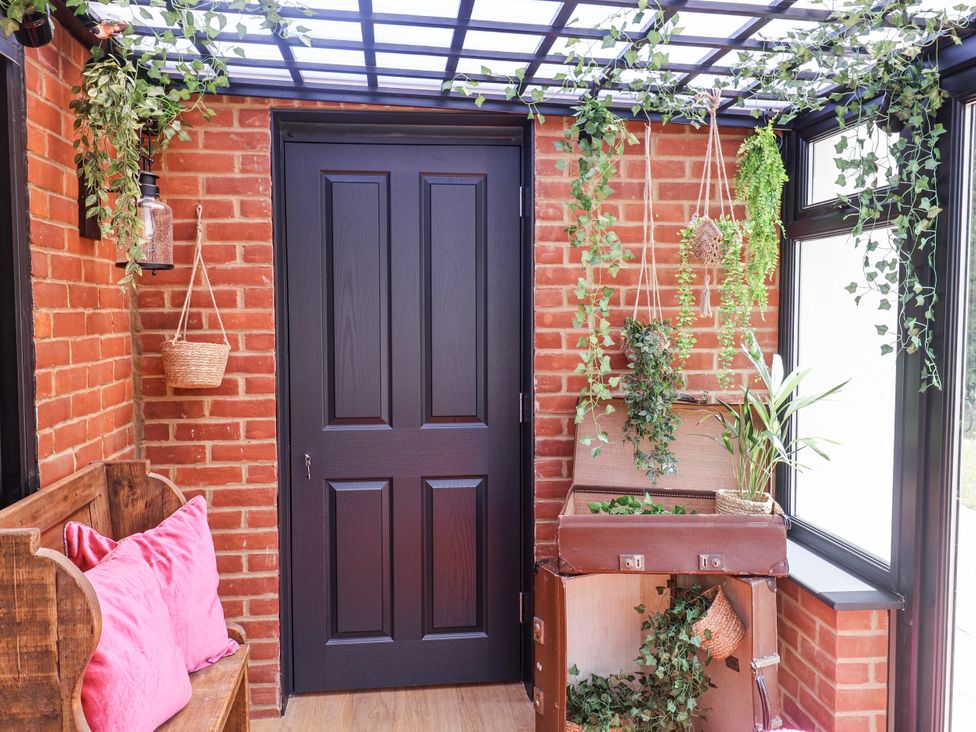 A conservatory with a bench and plants at Holly Farm near Brantham