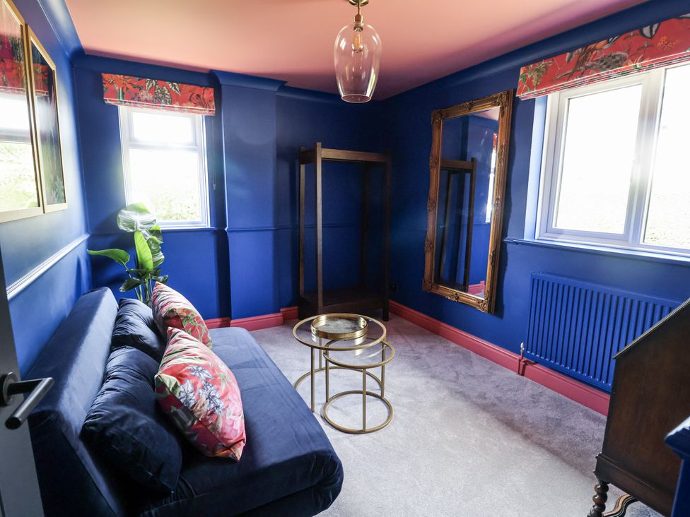 A sitting room with a blue sofa and plants at Holly Farm near Brantham