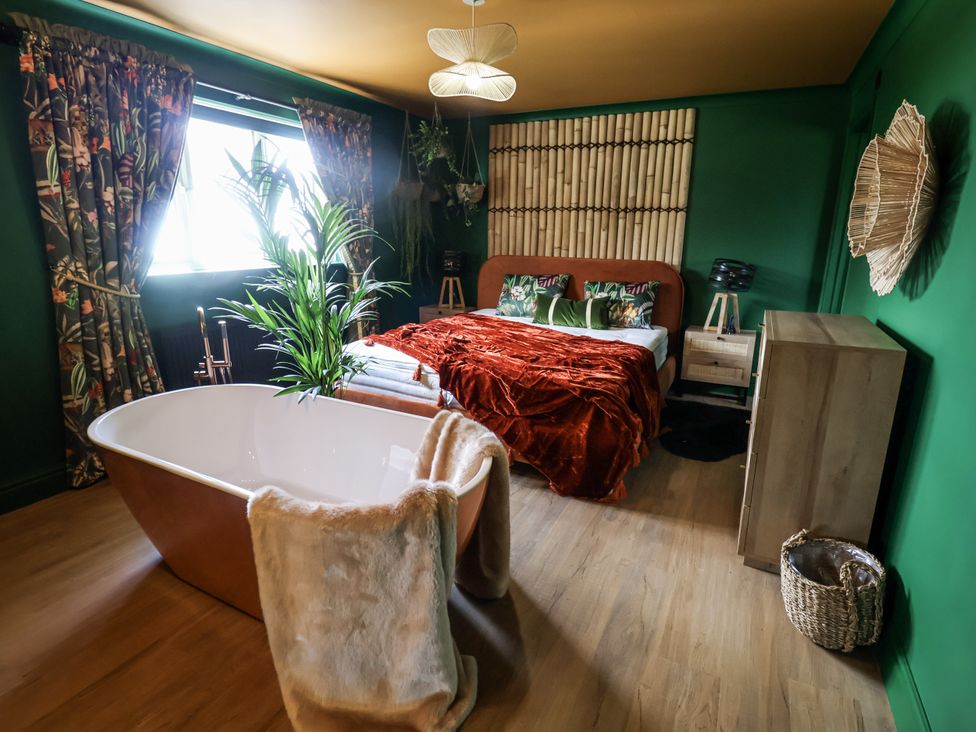 A bedroom with a bed and a bathtub at Holly Farm near Brantham