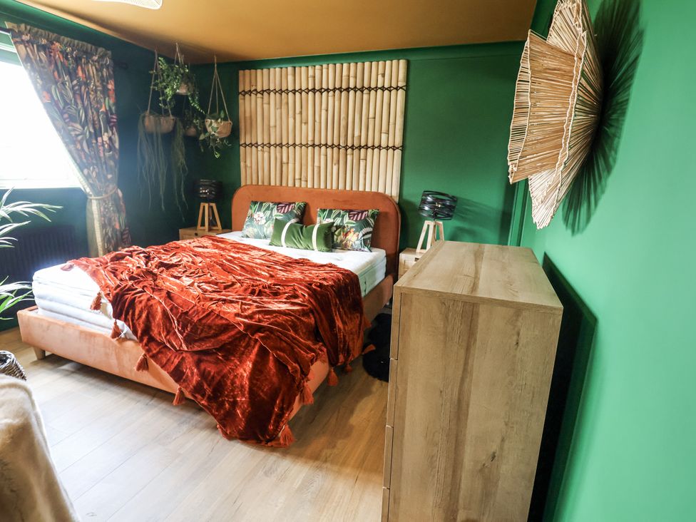 A bedroom with a bed and dresser at Holly Farm near Brantham