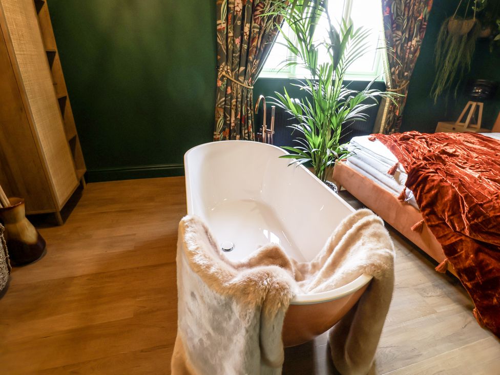 A bathtub with a blanket and a plant in a bathroom at Holly Farm near Brantham