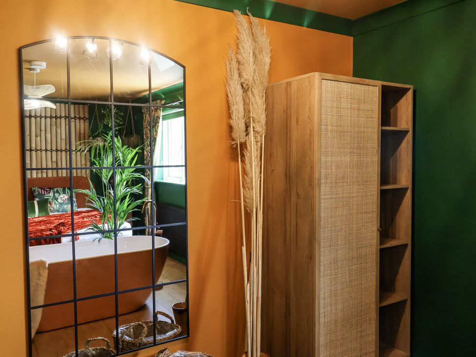 A bathroom with a bathtub and storage cabinet at Holly Farm near Brantham