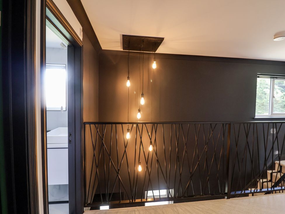 A hallway with lights and a view into a bathroom at Holly Farm near Brantham