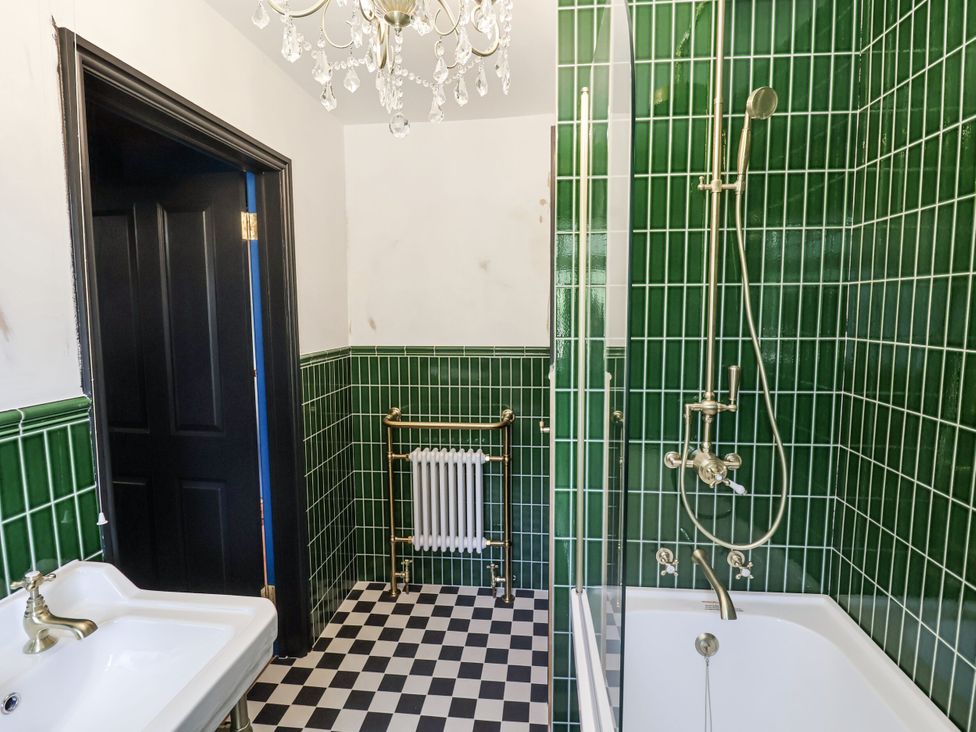 A bathroom with a bathtub, sink, and tiles at Holly Farm near Brantham