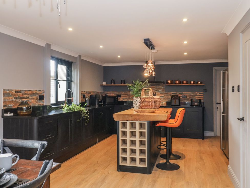 A kitchen with a counter and barstools at Holly Farm near Brantham