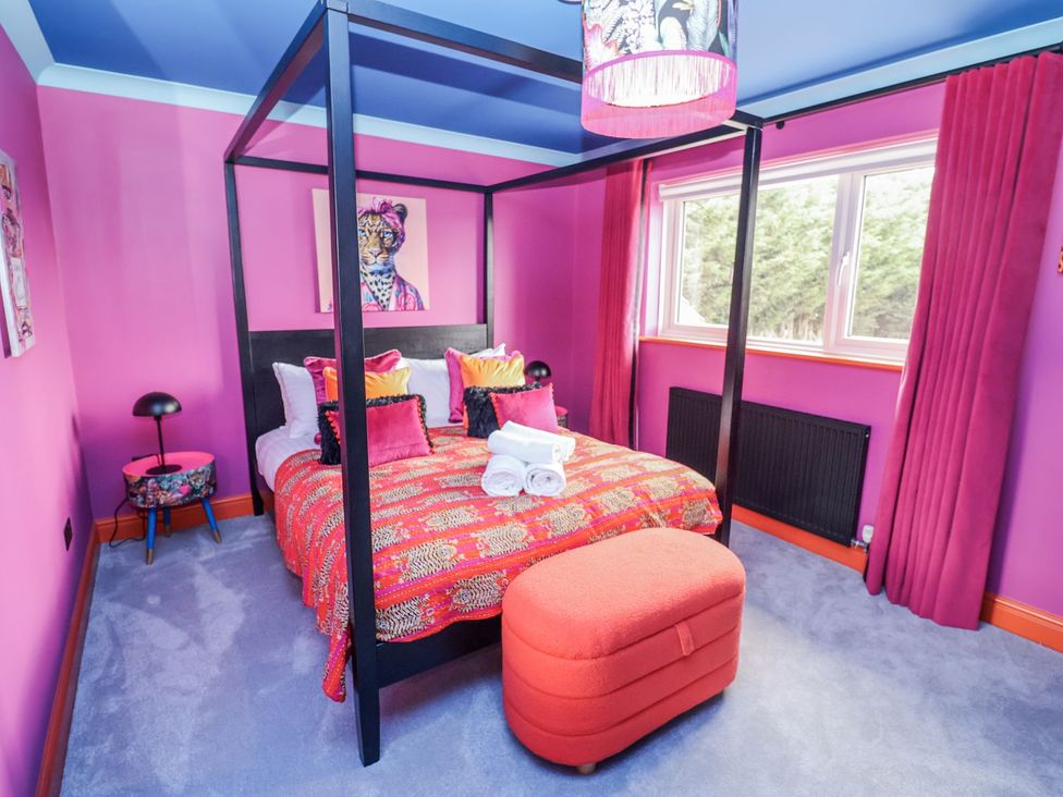 A bedroom with a four-poster bed and a window at Holly Farm near Brantham
