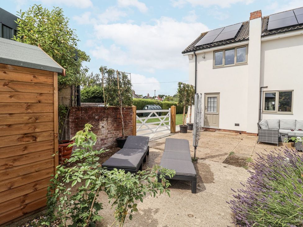 A garden with lounge chairs and a shed at Holly Farm near Brantham
