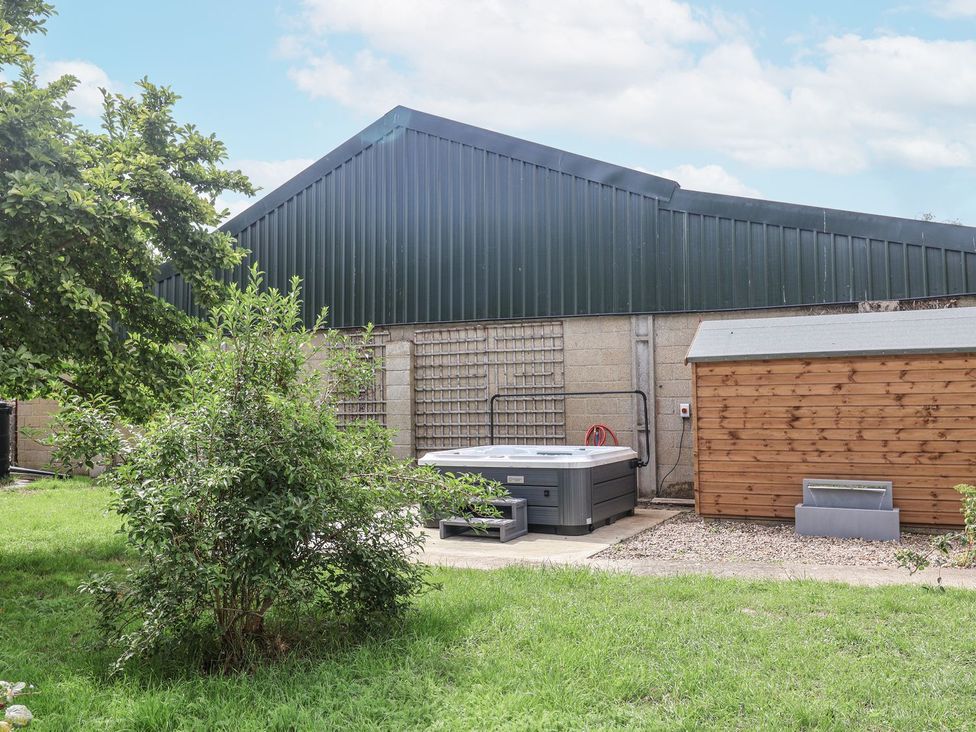 A garden with a hot tub and a shed at Holly Farm near Brantham