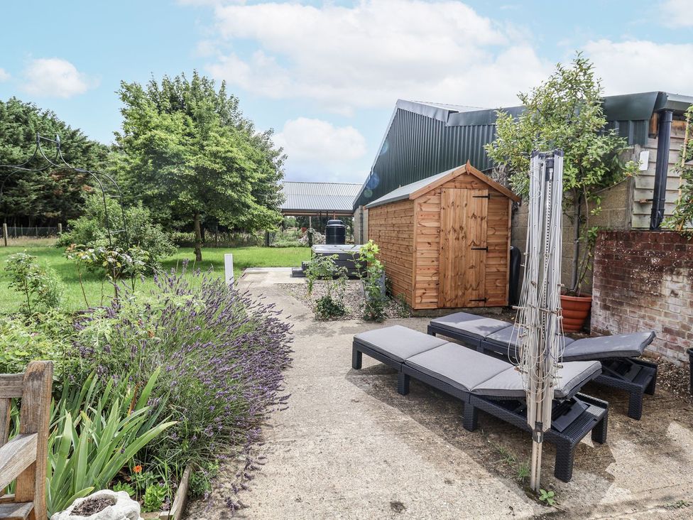 A garden with lounge chairs and a shed at Holly Farm near Brantham