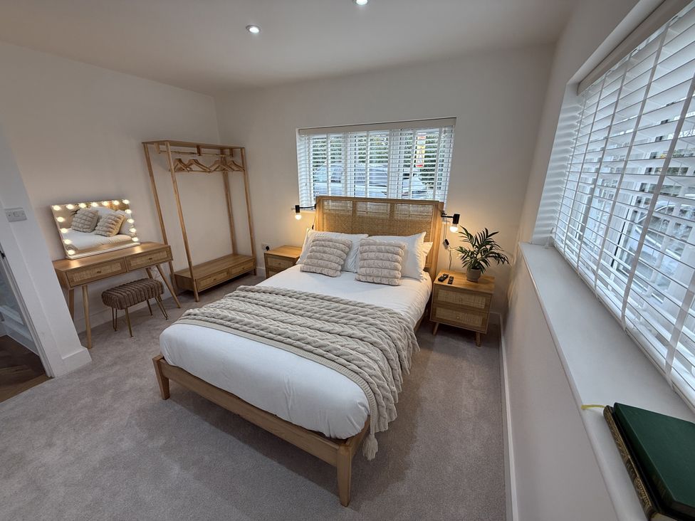 A bedroom with a bed, nightstand, mirror, and plant at Bader House in Ipswich