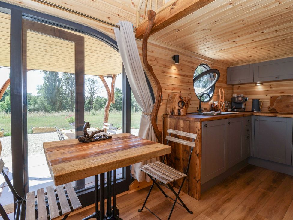 A kitchen with a table and stools at Bugley Pools Hideaway Bugley near Gillingham