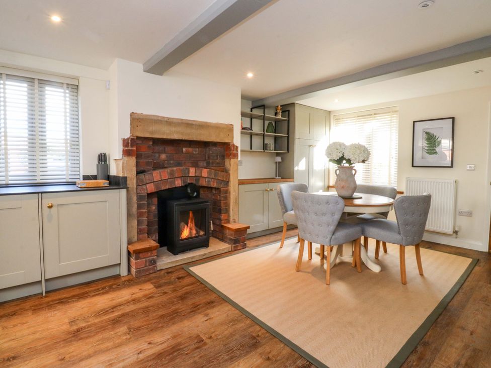 A dining room with a table and chairs near a fireplace at Cottage in 