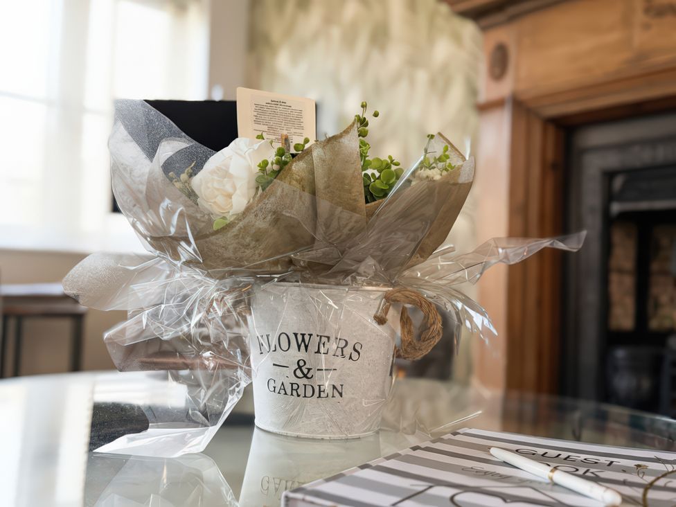 A bucket of flowers on a table with a guestbook and pen at Gardener's Cottage in Lytham St. Annes