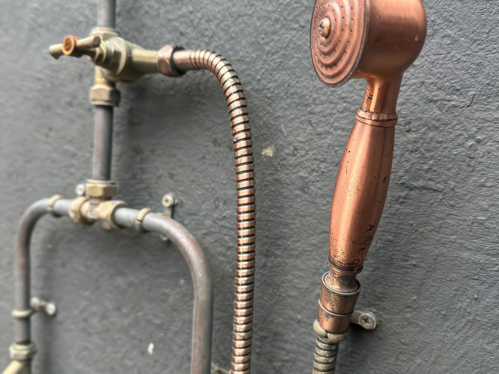 A spray nozzle and piping in a bathroom at The Garden Cottage and Carriage House Annagry, County Donegal
