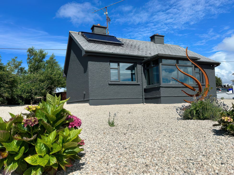 A house with a solar panel and sculpture in the garden at The Garden Cottage and Carriage House Annagry, County Donegal