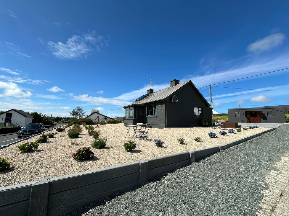 An outdoor area with a house and car at The Garden Cottage and Carriage House in Annagry, County Donegal