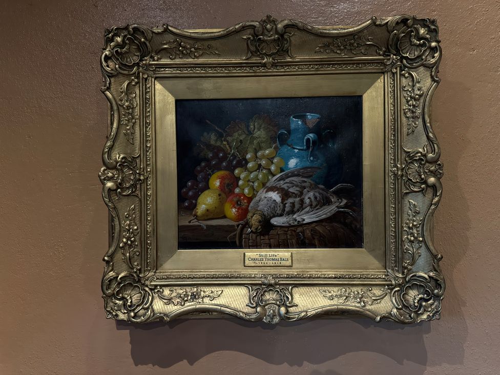 A painting of fruit and a bird in a frame at Cobble Stone Cottage near Leabgarrow, County Donegal