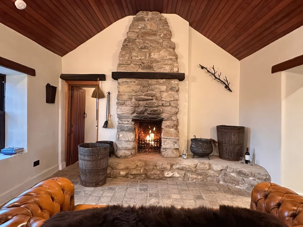 A living room with a stone fireplace and wooden features at Cobble Stone Cottage near Leabgarrow, County Donegal
