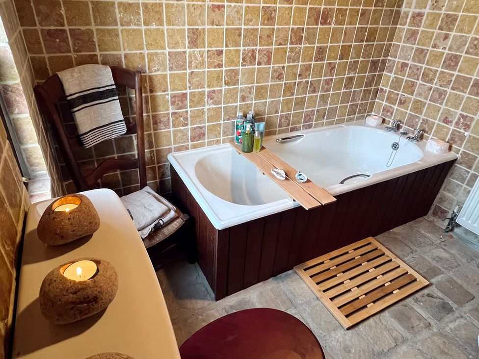 A bathroom with a bathtub and a chair at Cobble Stone Cottage near Leabgarrow, County Donegal
