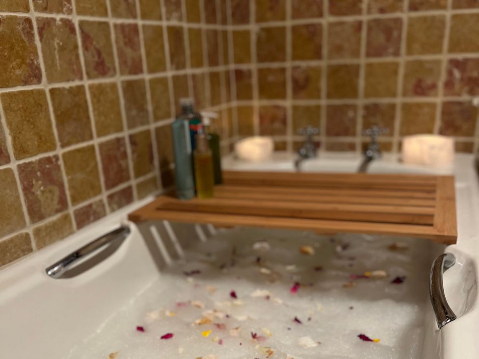 A bathtub with bath oils and candles at Cobble Stone Cottage near Leabgarrow, County Donegal