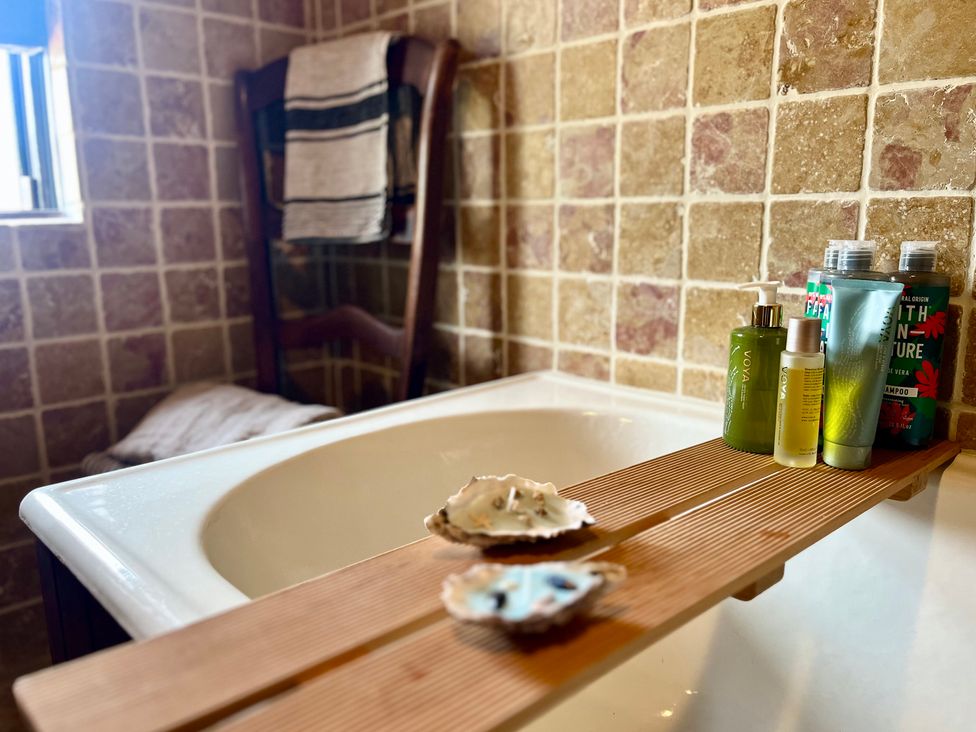 A bathroom with a bathtub and toiletries at Cobble Stone Cottage near Leabgarrow, County Donegal