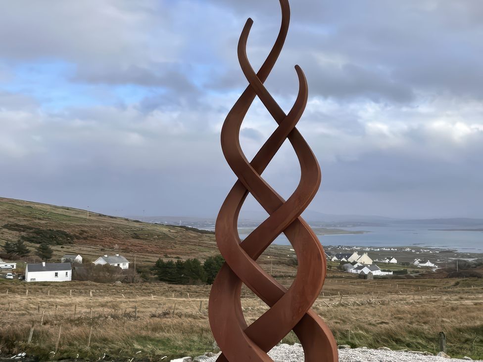 A sculpture in a landscape with hills and houses near water at Cobble Stone Cottage near Leabgarrow, County Donegal