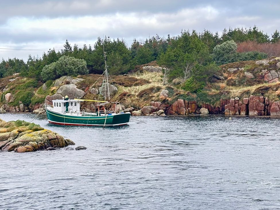A boat in the water with trees and rocks at Cobble Stone Cottage near Leabgarrow, County Donegal