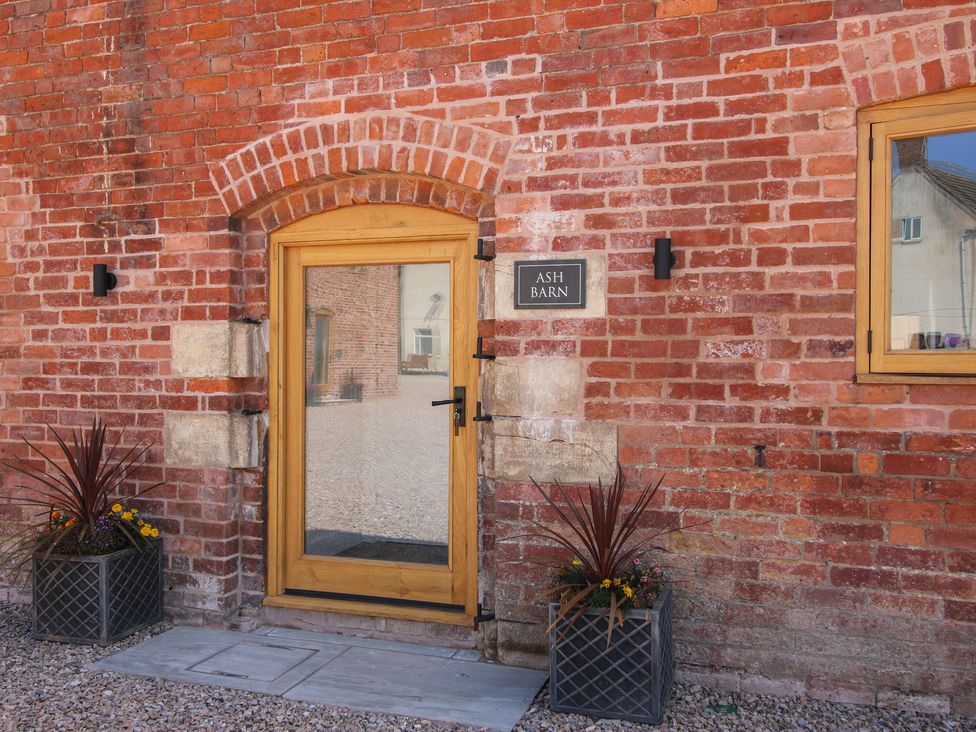 A door and window on a brick wall with a sign at Ash Barn in Shrewsbury
