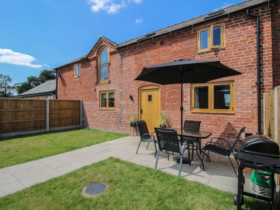 A garden with a table, chairs, and barbecue grill at Ash Barn in Shrewsbury