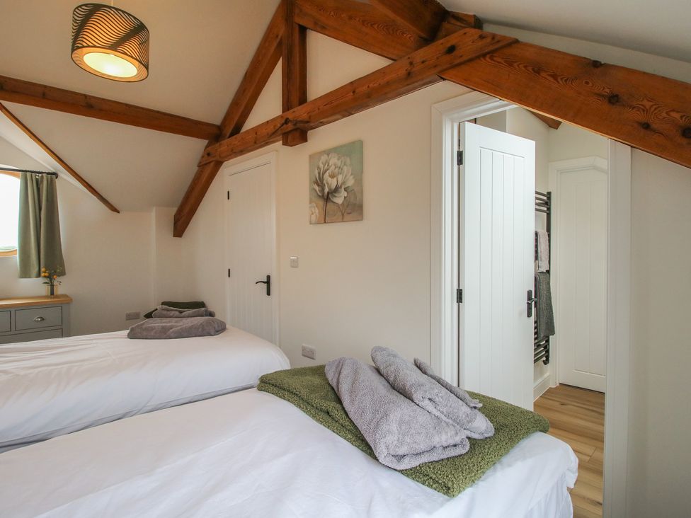 A bedroom with two beds and a door at Ash Barn near Northwood near Wem