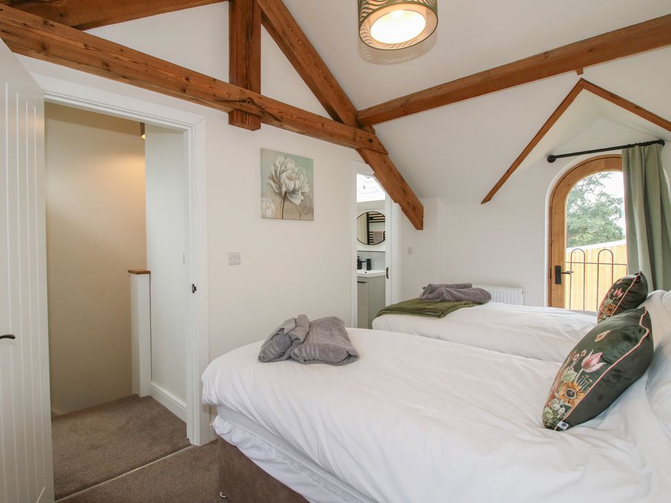 A bedroom with two beds and a door leading outside at Ash Barn Northwood near Wem