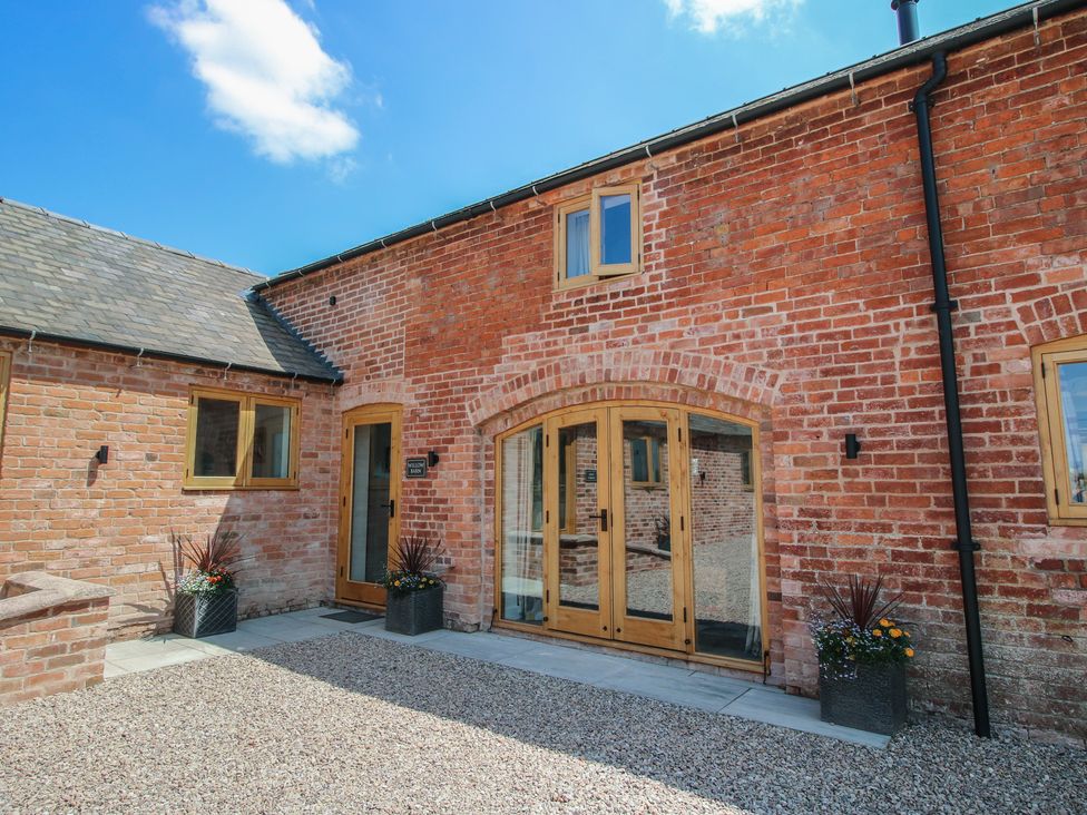 An entrance with wooden doors and gravel driveway at Willow Barn in Shrewsbury