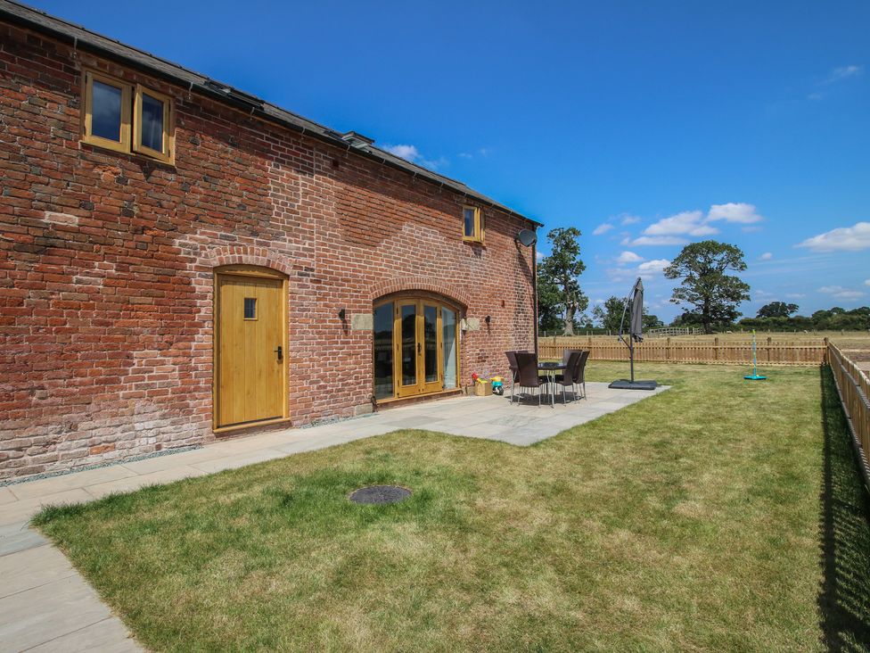 A garden with a brick wall and outdoor furniture at Willow Barn in Shrewsbury