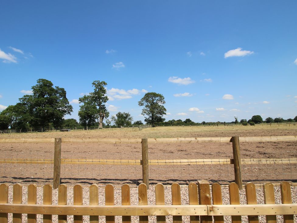 An outdoor field with a wooden fence at Willow Barn in Shrewsbury