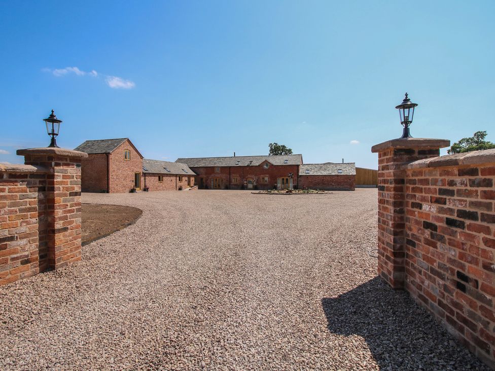 An outdoor area with a gravel driveway and brick buildings at Willow Barn in Shrewsbury