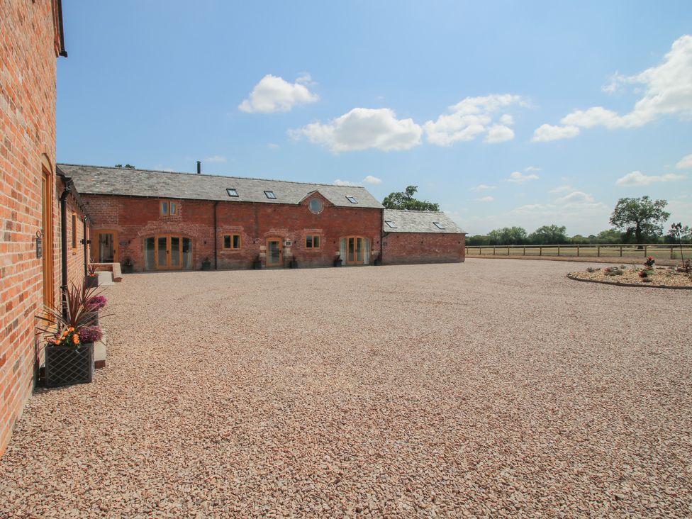 An outdoor area with a large gravel space and buildings at Willow Barn in Shrewsbury