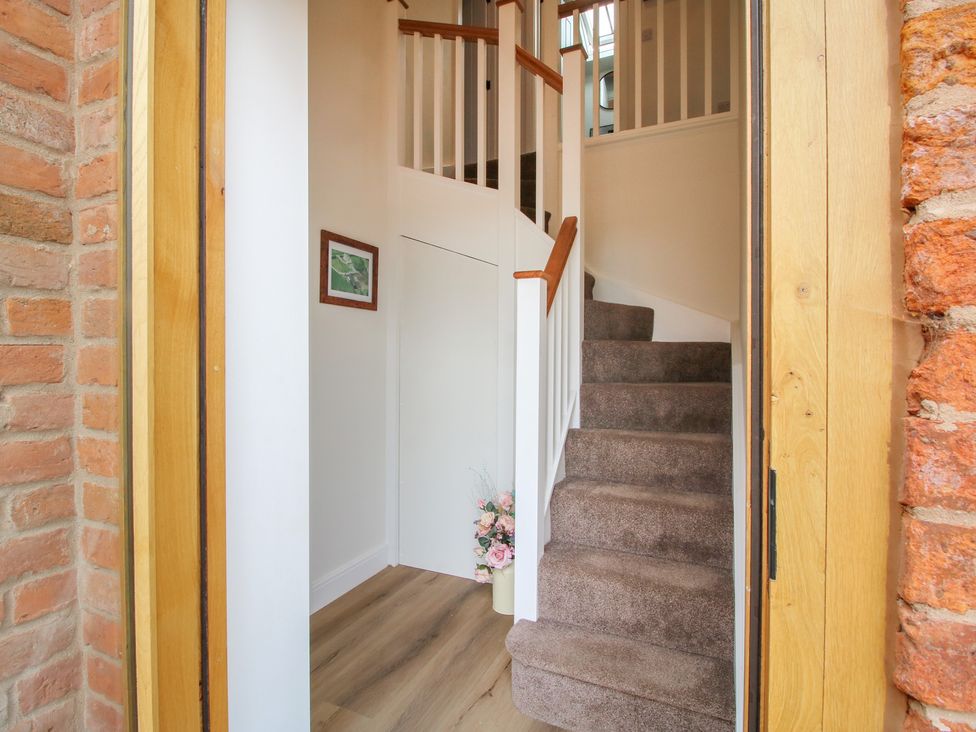 A hallway with a staircase and a floral arrangement at Willow Barn near Wem