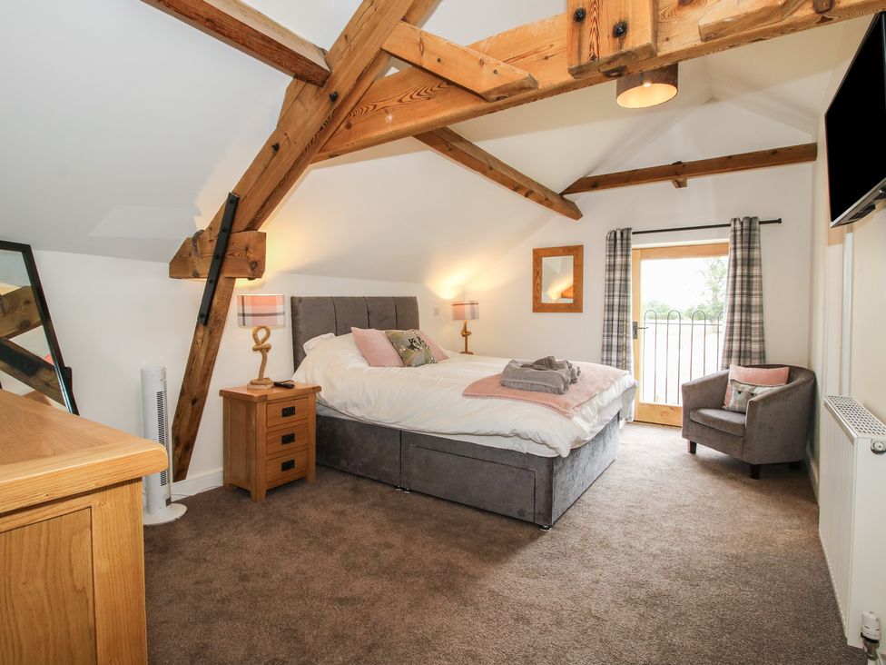 A bedroom with a bed, nightstand, and chair at Willow Barn in Northwood near Wem
