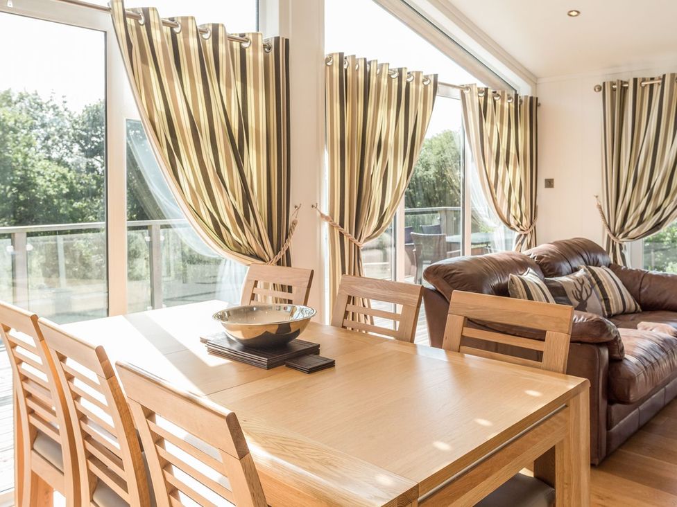 A dining room with a table and chairs, and a couch at 2 Tree Tops in Lanreath