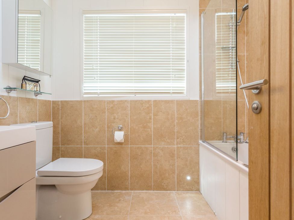A bathroom with a toilet and bathtub at 2 Tree Tops in Lanreath